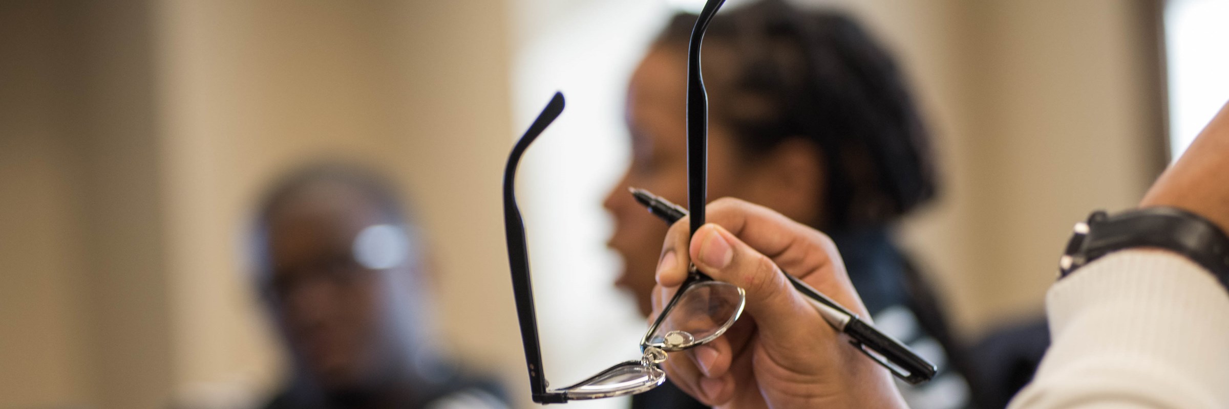 Picture of people talking with a pair of eyeglasses focused in the front