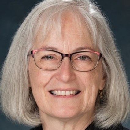 Headshot of Carole Breitenberger wearing red glasses and smiling