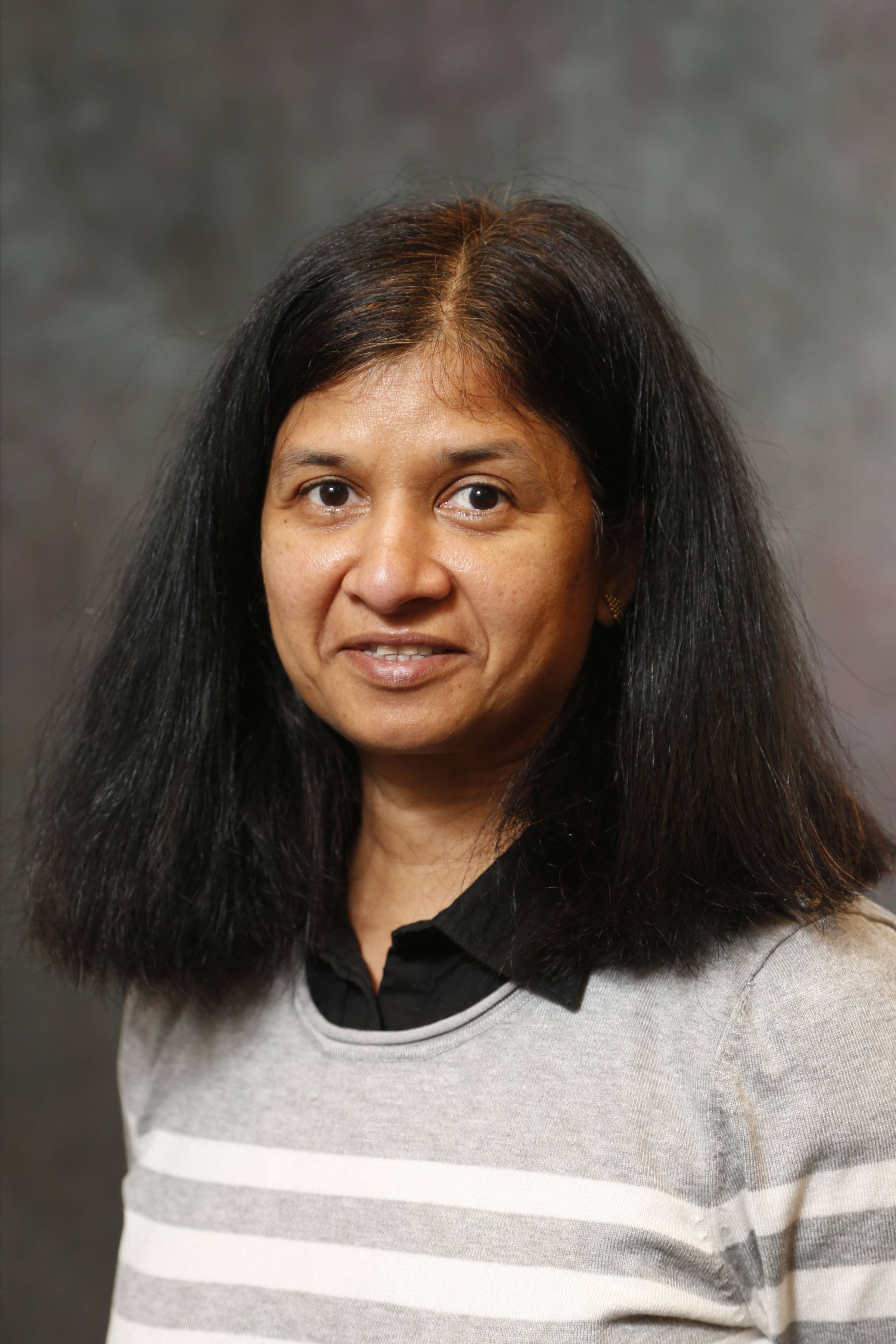 Headshot of Gunjan Agarwal smiling wearing a gray and white striped blouse