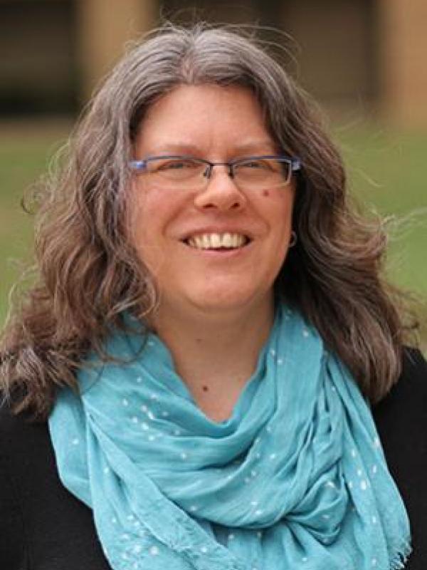 Headshot of Lisa Neilson smiling wearing a blue scarf around her neck and glasses