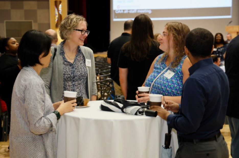 Shanna Jaggars chats cheerfully with members of the Institutional Research and Planning team at office function.