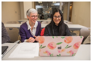 Beth Black with a student who is working on a laptop.