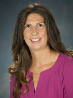 Dr. Kelly Purtell's headshot wearing a pink top and wavy hair