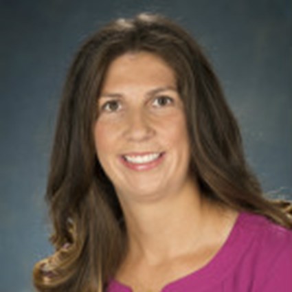Dr. Kelly Purtell's headshot wearing a pink top and wavy hair
