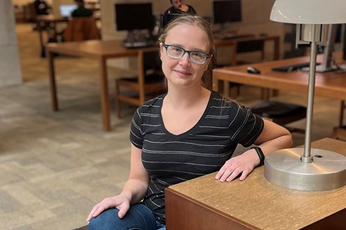 Carolyn Johns sitting at a desk with a small lamp on it