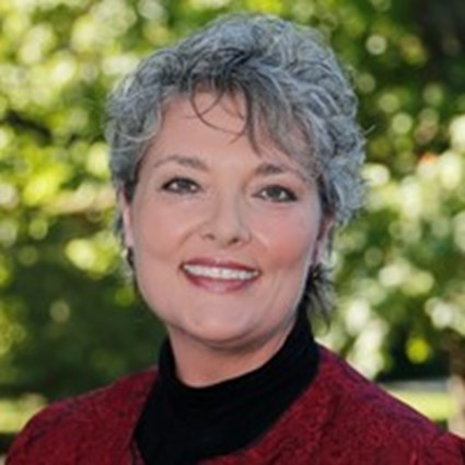 Headshot of Teresa Johnson wearing a black turtleneck and red jacket.