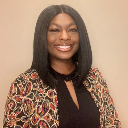 Headshot of Imani Reynolds wearing a black blouse and colorful jacket.