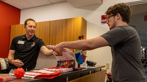 Person with a friendly smile handing items to another person