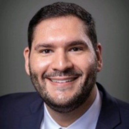 A headshot of Marcos D. Rivera wearing business attire