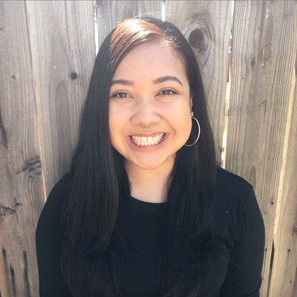 A headshot of Rebecca Cepeda wearing hoop earrings and a black shirt