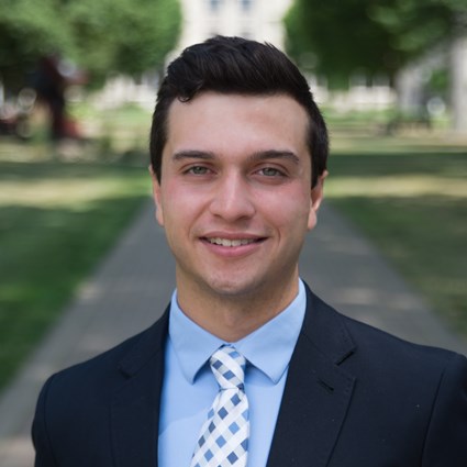 A headshot of Marcus Carano in the middle of Ohio State wearing business attire
