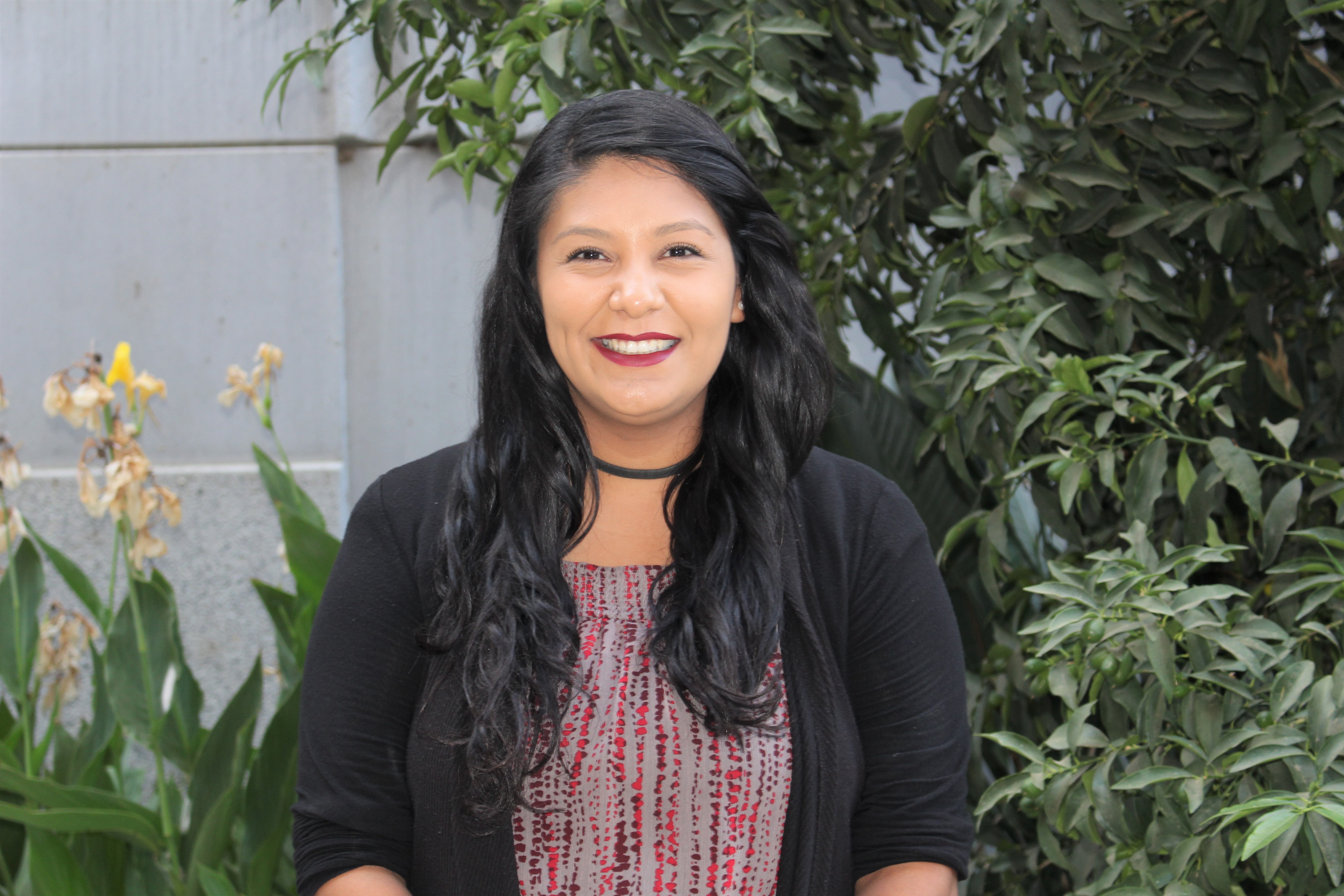 Headshot of Igdalia with long dark hair, a red blouse, and a black cardigan.