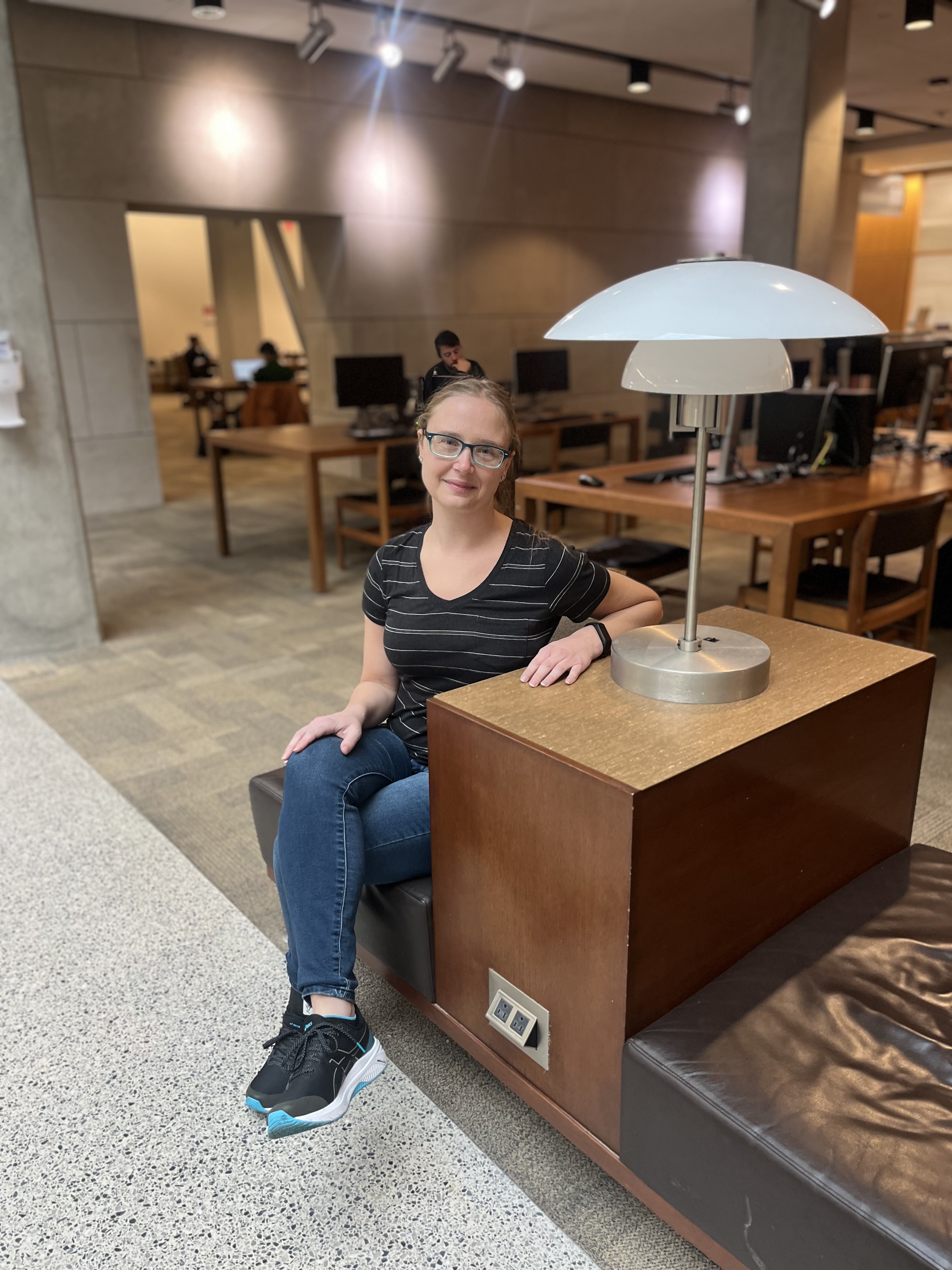 Carolyn Johns sits at a desk with a small lamp on it