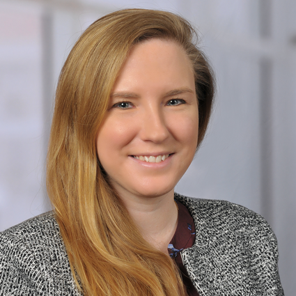 Headshot of Tasha Posid smiling with a gray suit