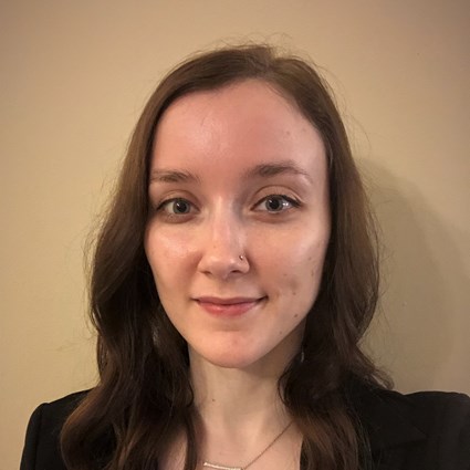 A headshot of Elizabeth Hance with wavy hear and a black blazer