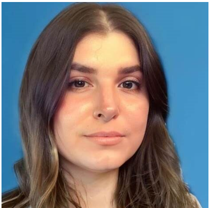 Headshot of woman faintly smiling at camera in front of a blue background.