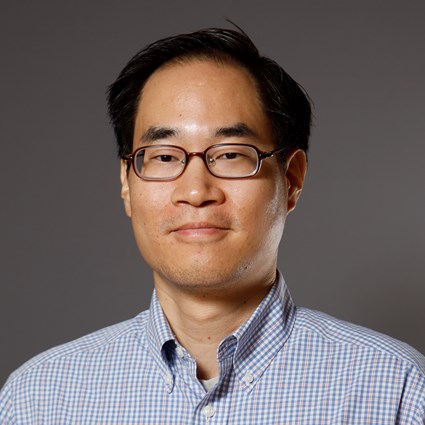 Headshot of Benjamin Ahn wearing a blue checkered dress shirt.