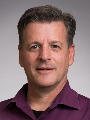 Headshot of Vincent Roscingo wearing a burgundy shirt and smiling