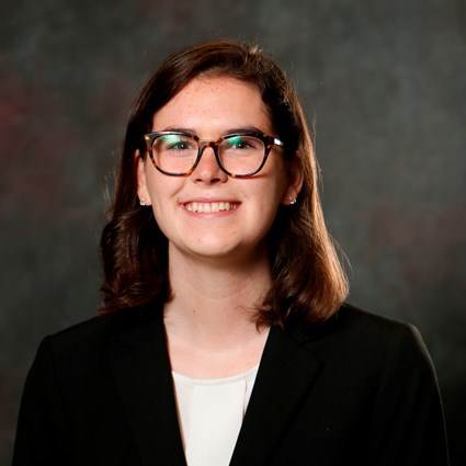 A headshot of Caroline Karwisch wearing glasses and a black blazer